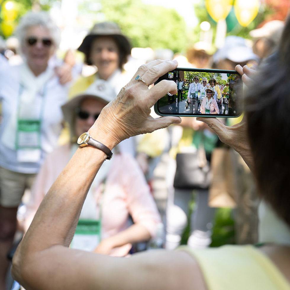 A person taking a photo with a phone of a group of Reunion attendees in the background