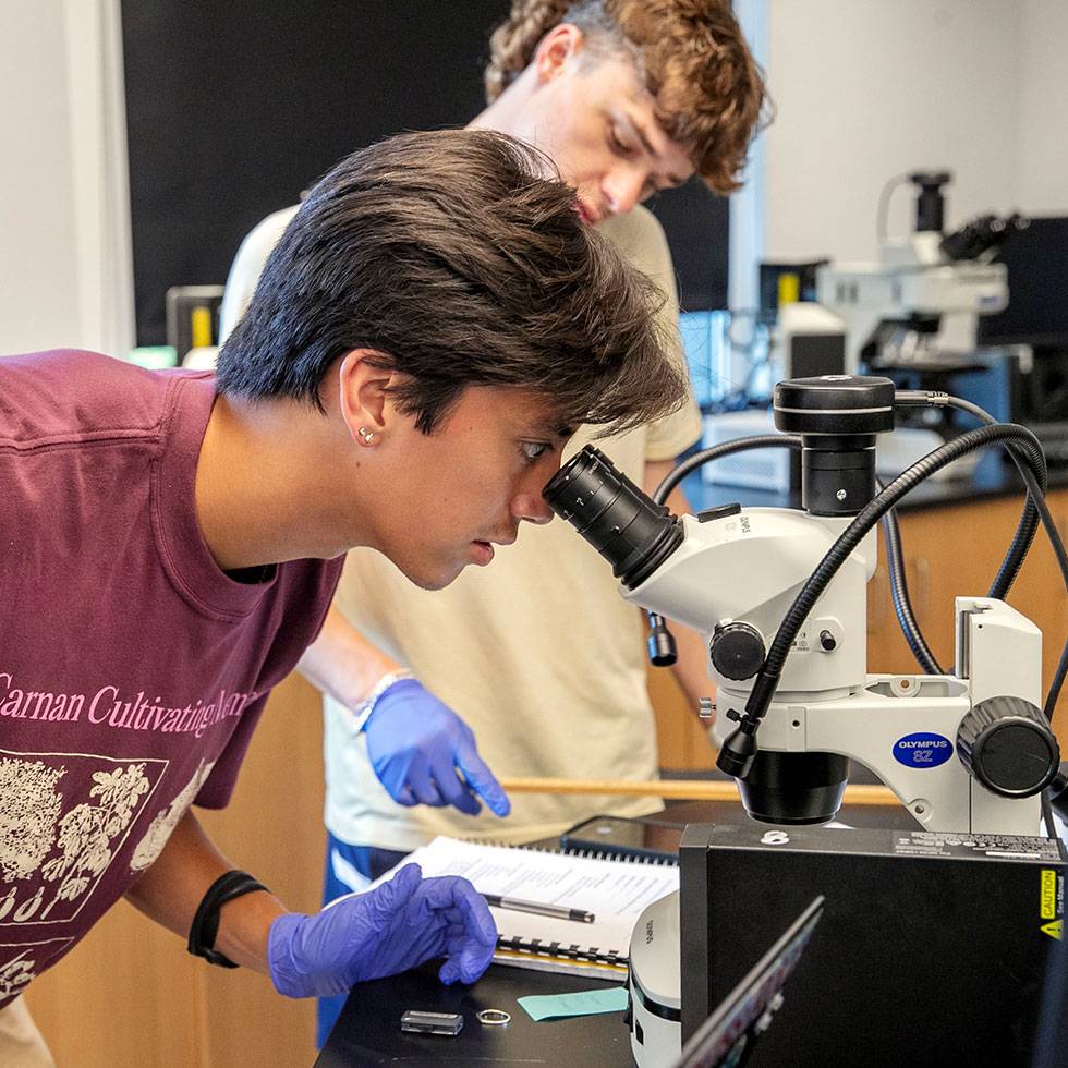 Student looks through a microscope in a lab 