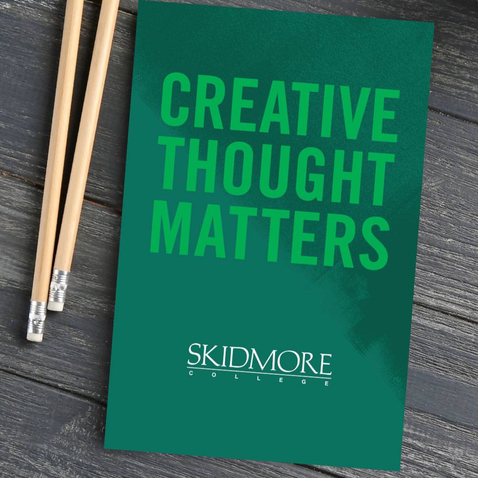 Image of an Admissions booklet that reads "Creative Thought Matters" on a wooden table, with two pencils next to it.
