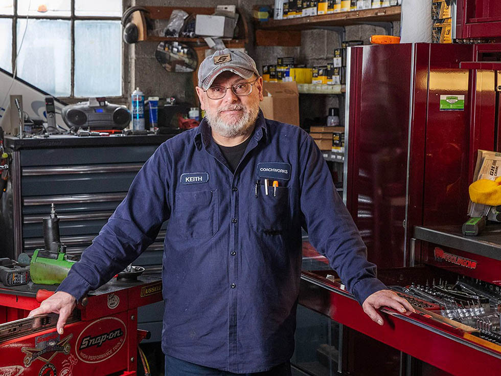 Keith Murray stands in a workshop with red shelving and tools.