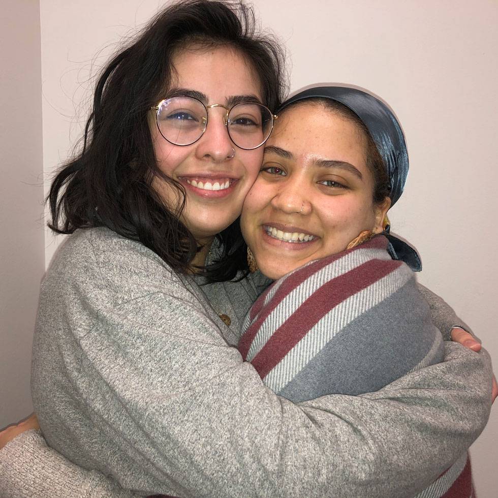 Two students embrace with big smiles