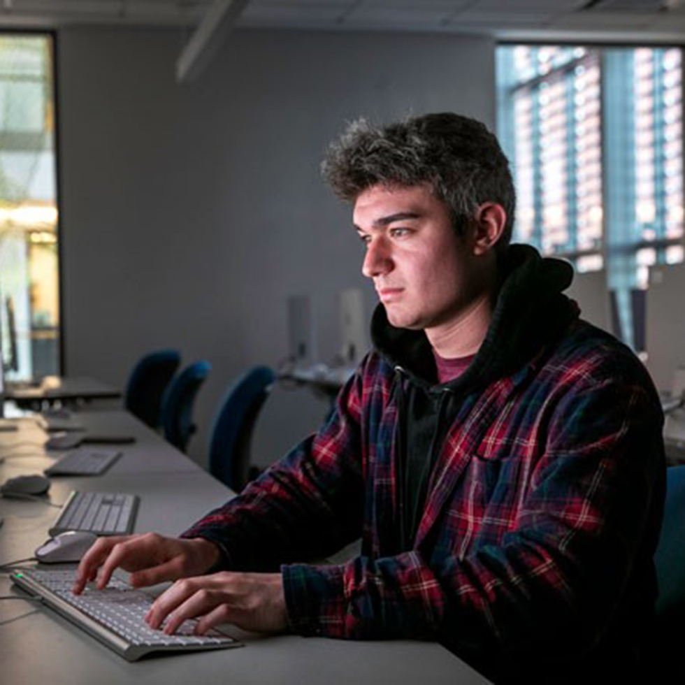Dylan Telano '23 sitting at a keyboard typing.