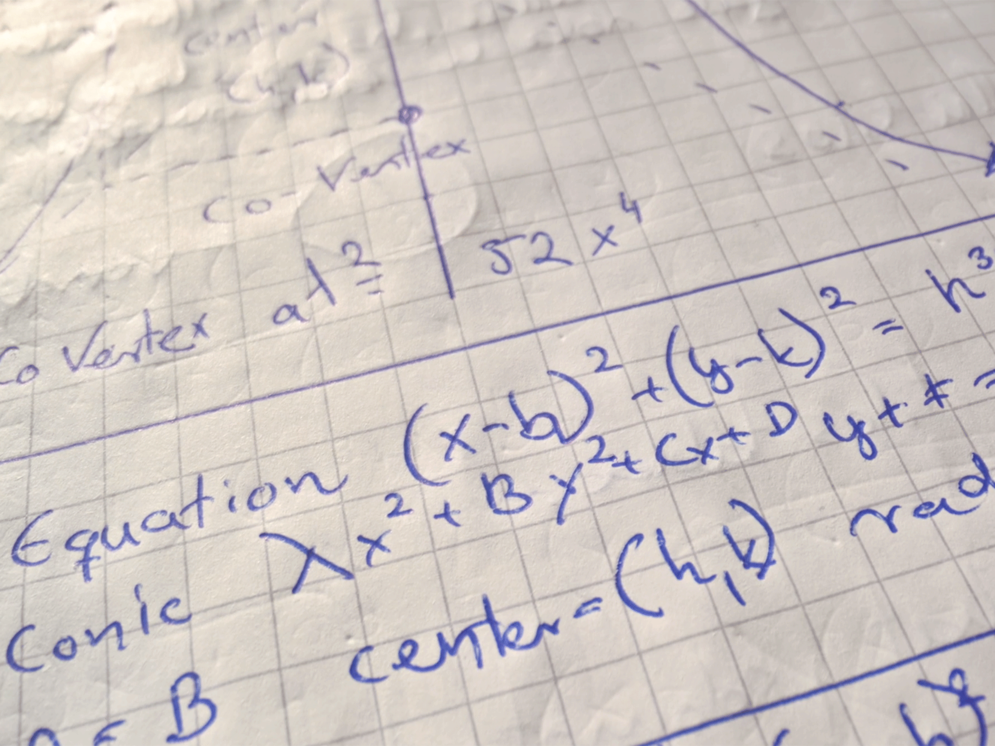 Math equations in blue ink handwriting on graph paper