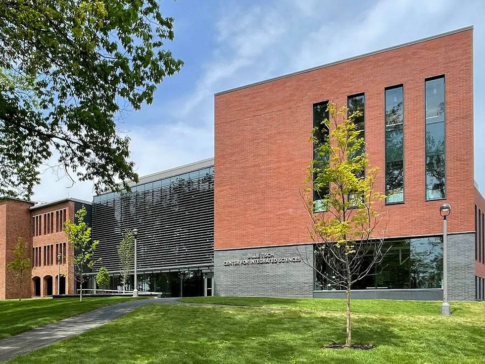 Exterior view of the Billie Tisch Center for Integrated Sciences on a beautiful blue sky day with a green lawn and blooming trees
