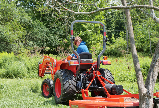 Malcolm Ash '25 rides a tractor at The Coop in Rupert, Vermont