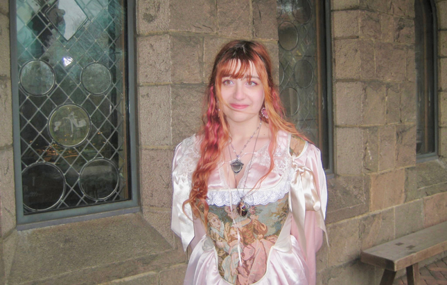Abby Savitz stands in a dress outside a stone building