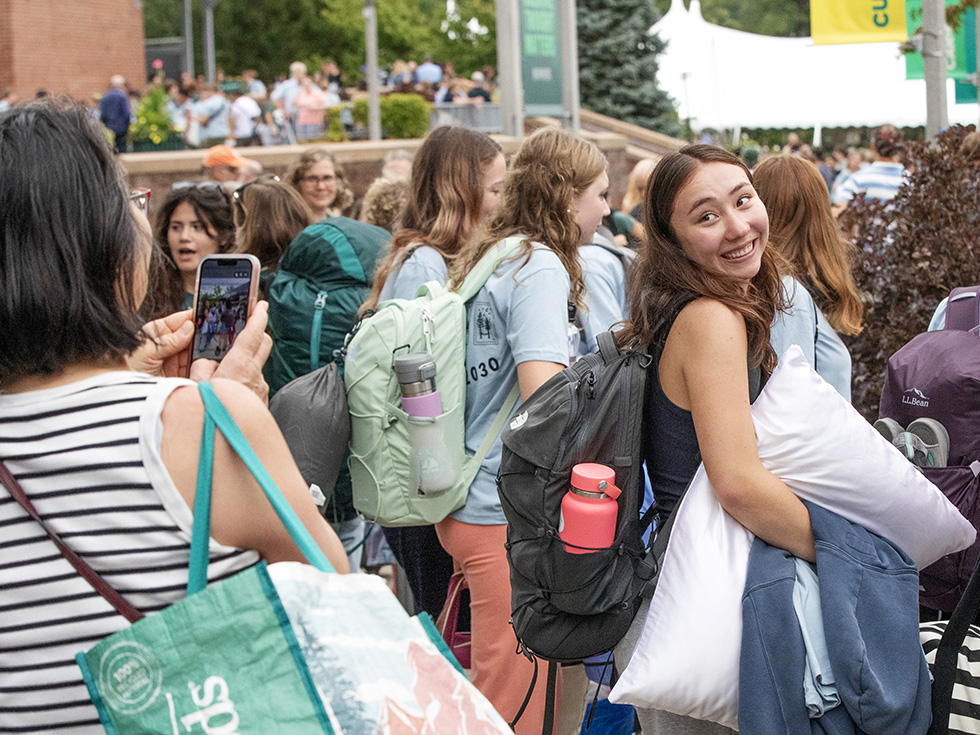 A family member taking at photo as students board buses for Pre-Orientation