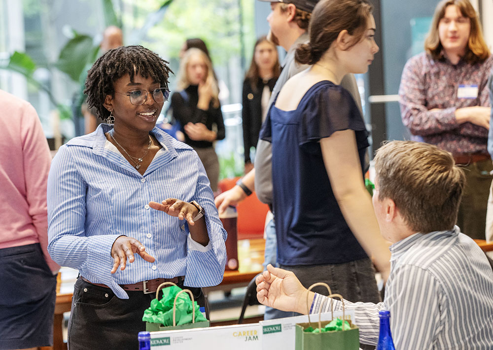 A student stands and speaks with a representative sitting at a table at Career Jam.