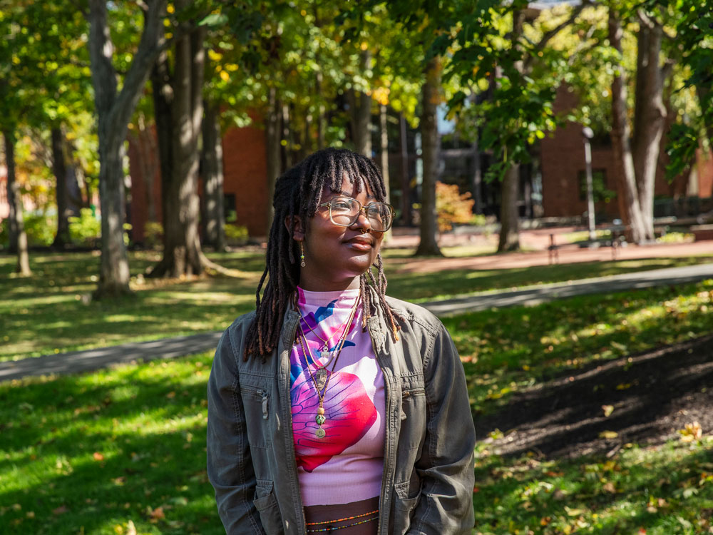 Sela Safo stands in front of a green lawn and green trees on the Skidmore campus