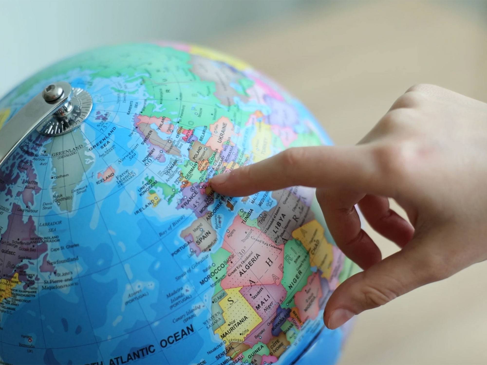 A finger points to a location on a globe