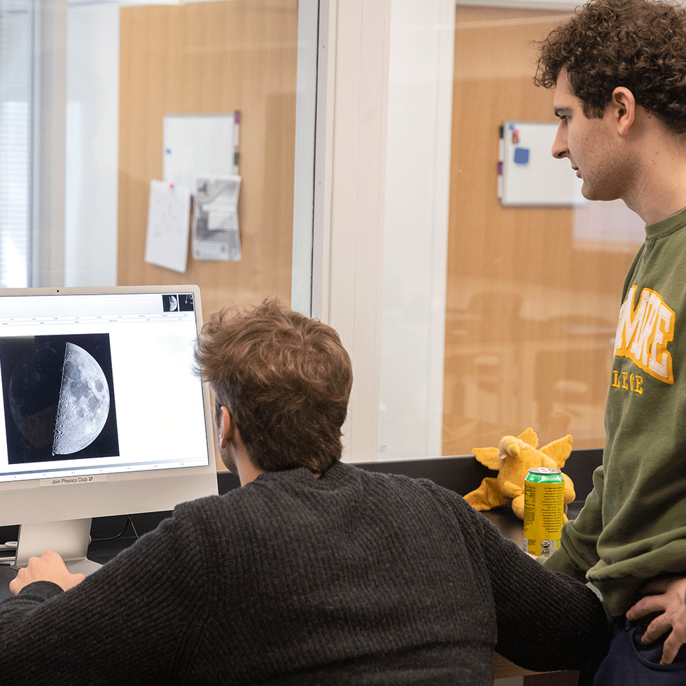 Two students look at an image of the moon on a computer screen