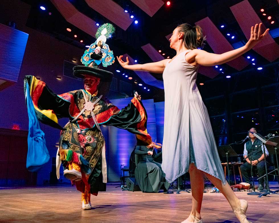 A dancer performs beside a colorfully costumed performer and musicians onstage at Zankel Music Center.